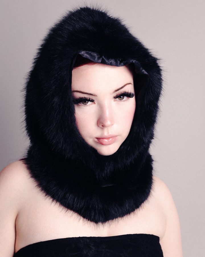 Model in a black fur hood against a pale studio backdrop